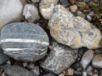 Grauer Stein mit weißen Bändern neben hautfarbenem mit hellen Einschlüssen